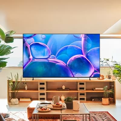Großer Fernseher mit buntem Blasenmotiv in modernem Wohnzimmer mit Regal, Pflanzen und gedecktem Couchtisch