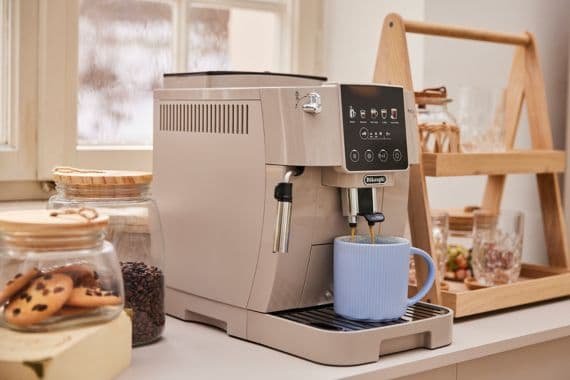 Kaffeemaschine auf Küchenarbeitsplatte neben Keksglas und blauem Kaffeebecher.